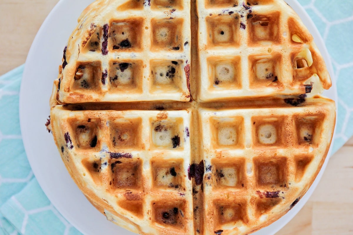 The top view of a stack of waffles filled with blueberries.