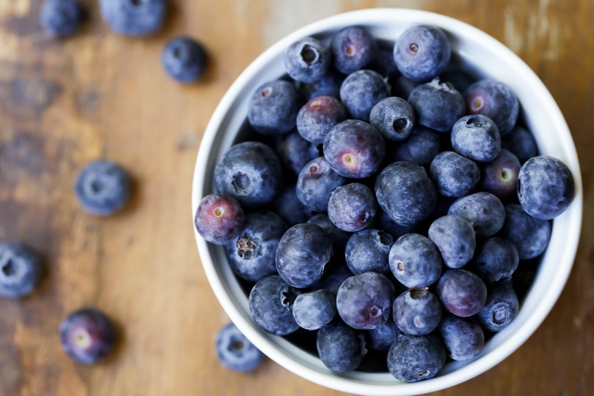 The top view of a white bowl filled with fresh blueberries.