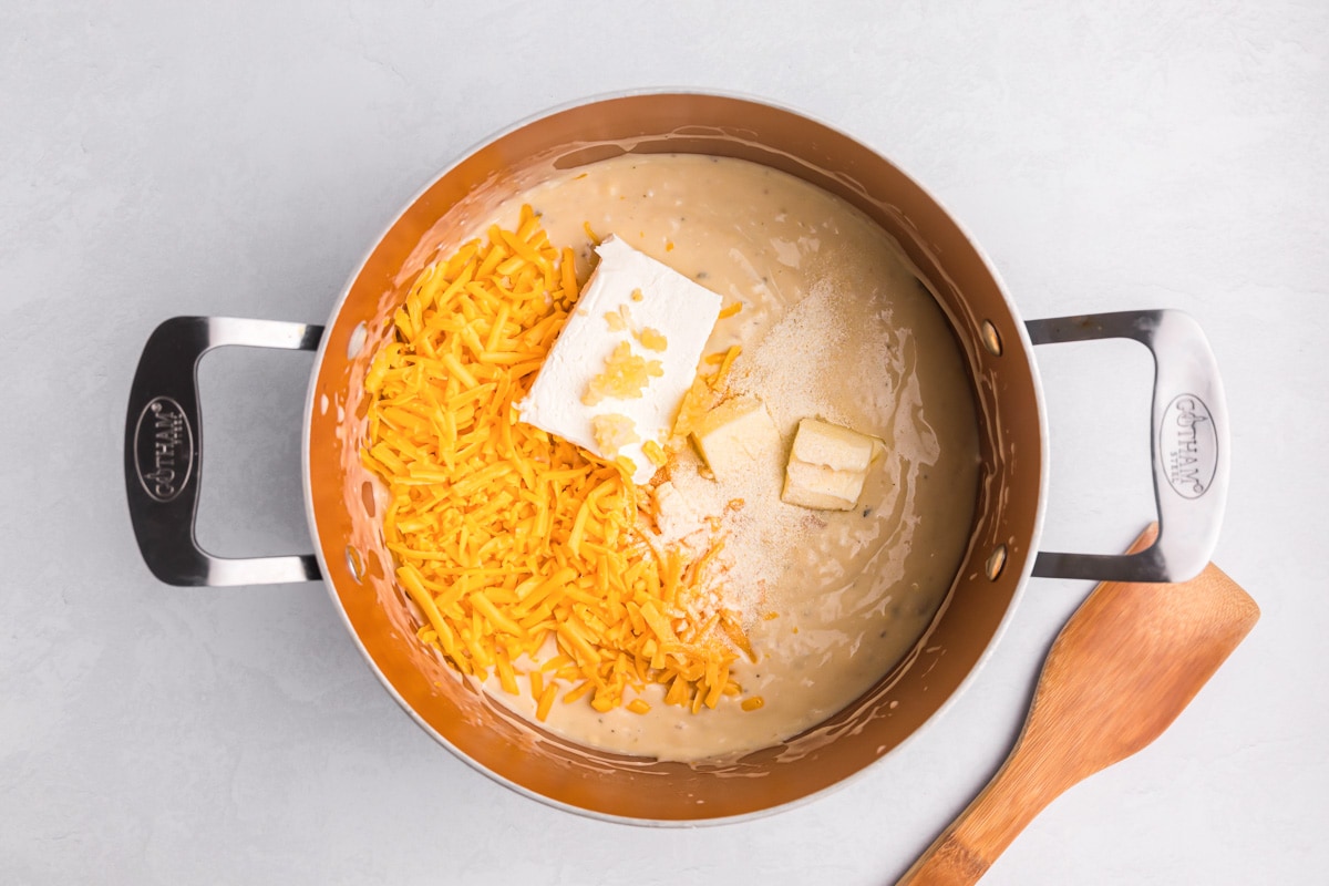 Cream of soups, shredded cheese, butter, and cream cheese in a pot.