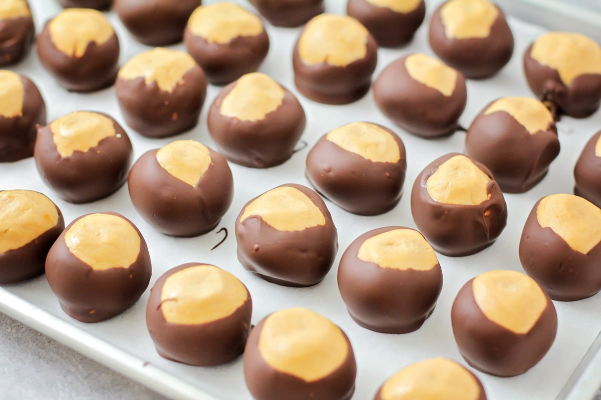 A sheet lined with peanut butter balls dipped in chocolate.