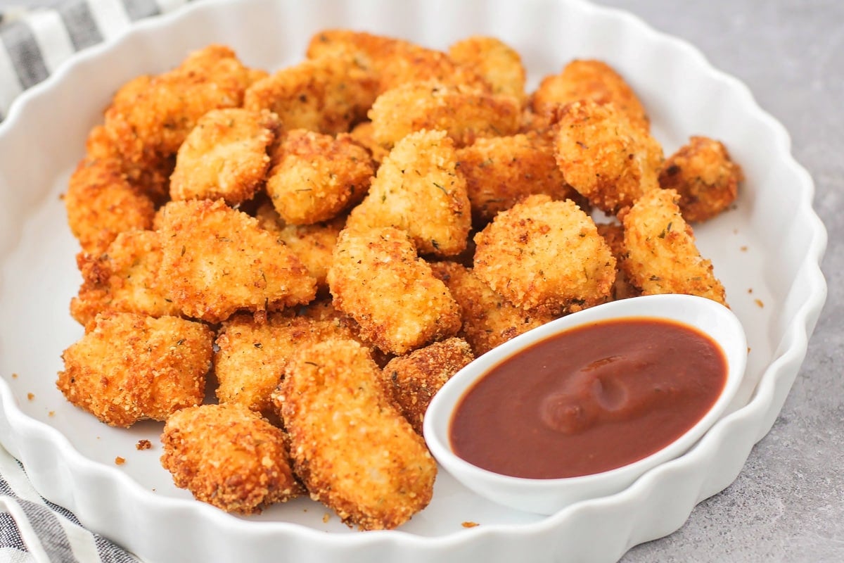 Homemade chicken nuggets on white plate with bbq sauce.