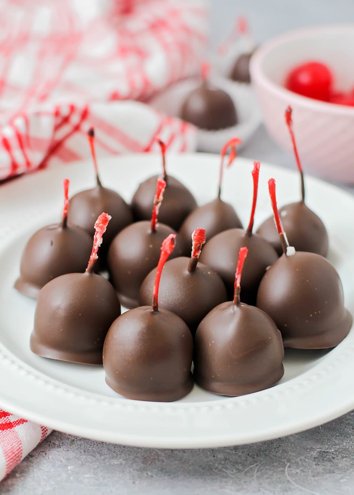 Close up of chocolate covered cherries on a white plate.