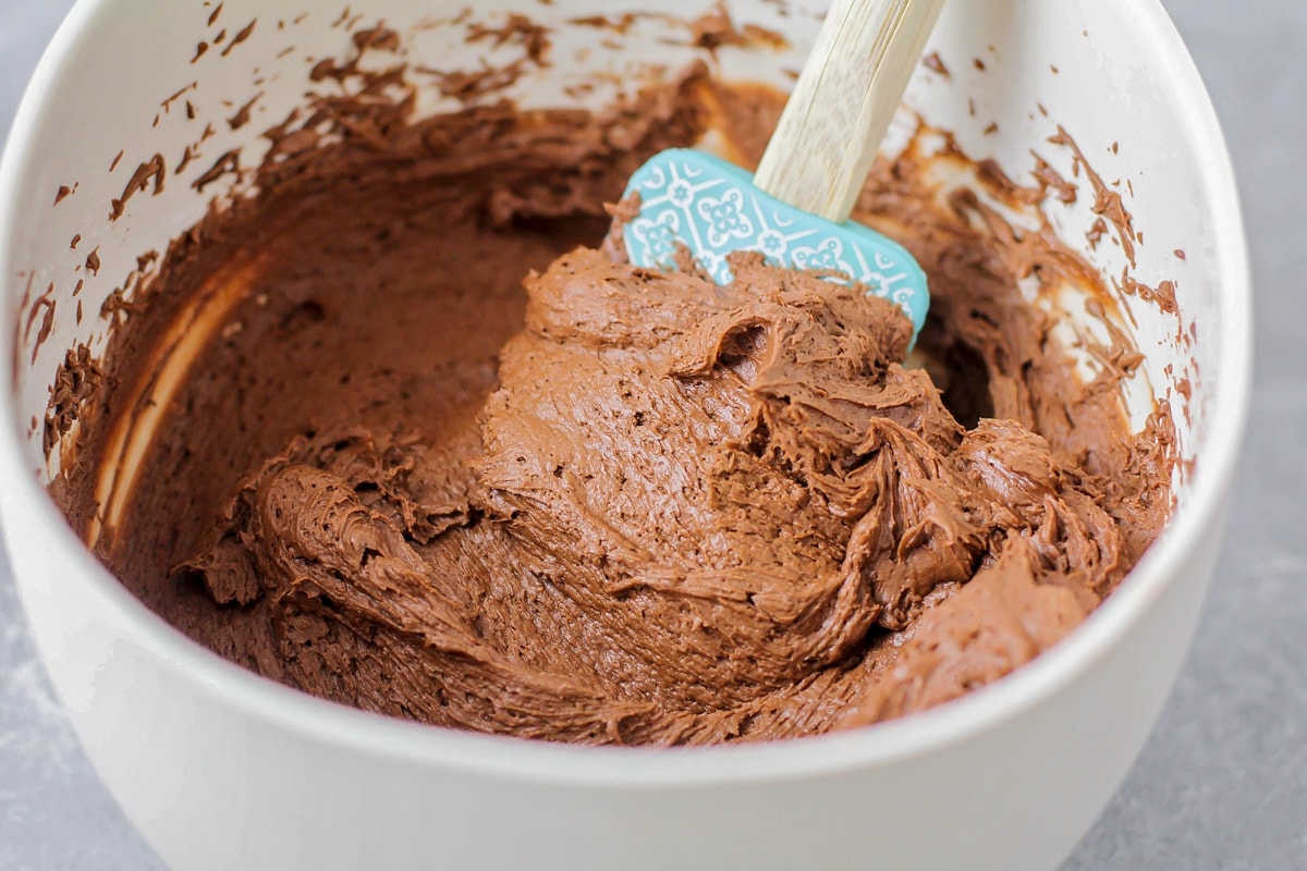 Using a blue spatula to mix chocolate icing.
