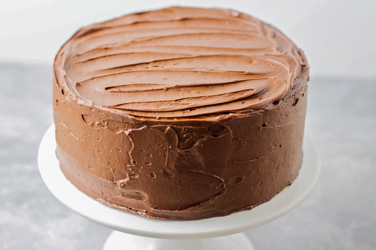 A two tiered cake covered in chocolate frosting.