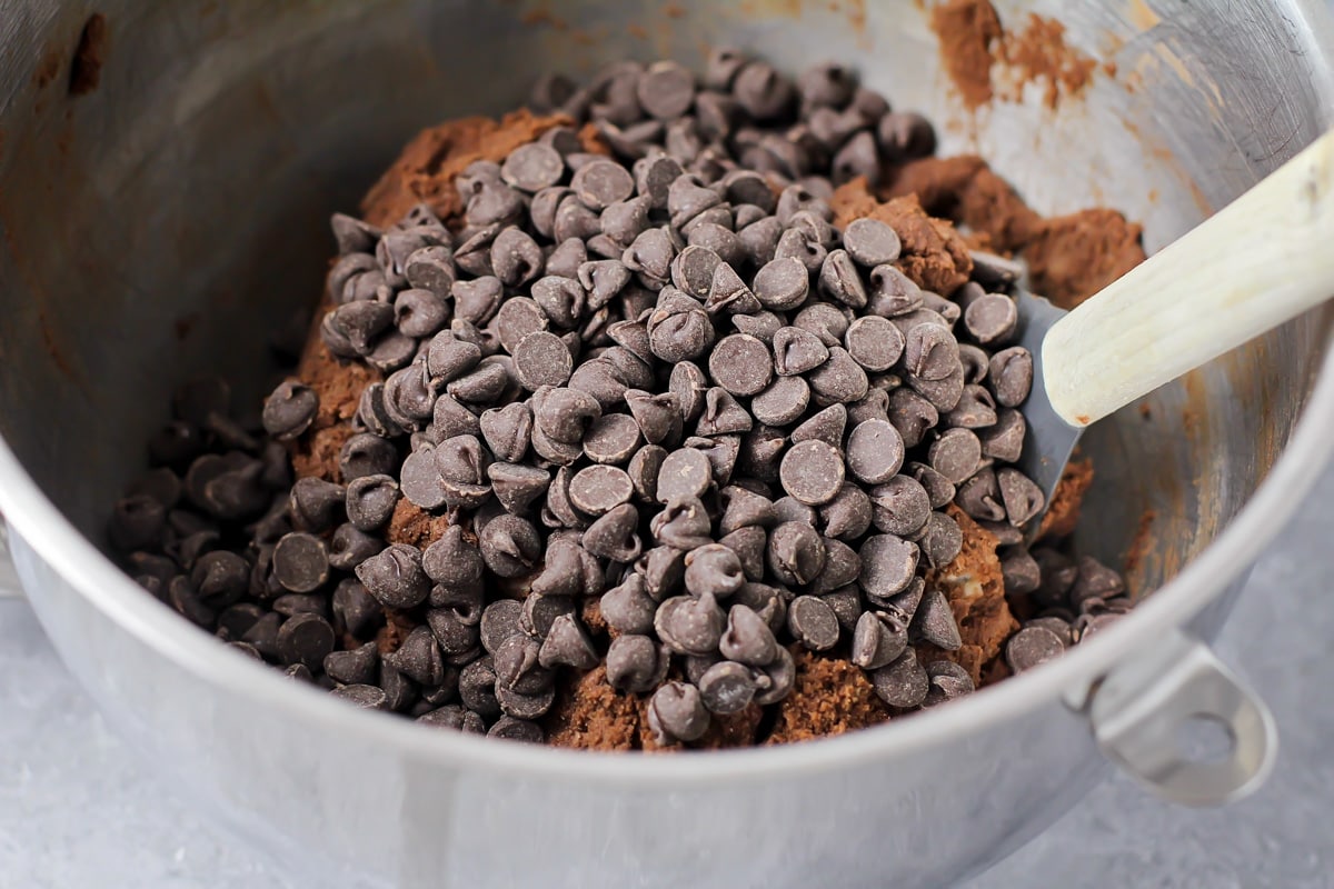 Adding chocolate chips to a chocolate cookie dough batter.