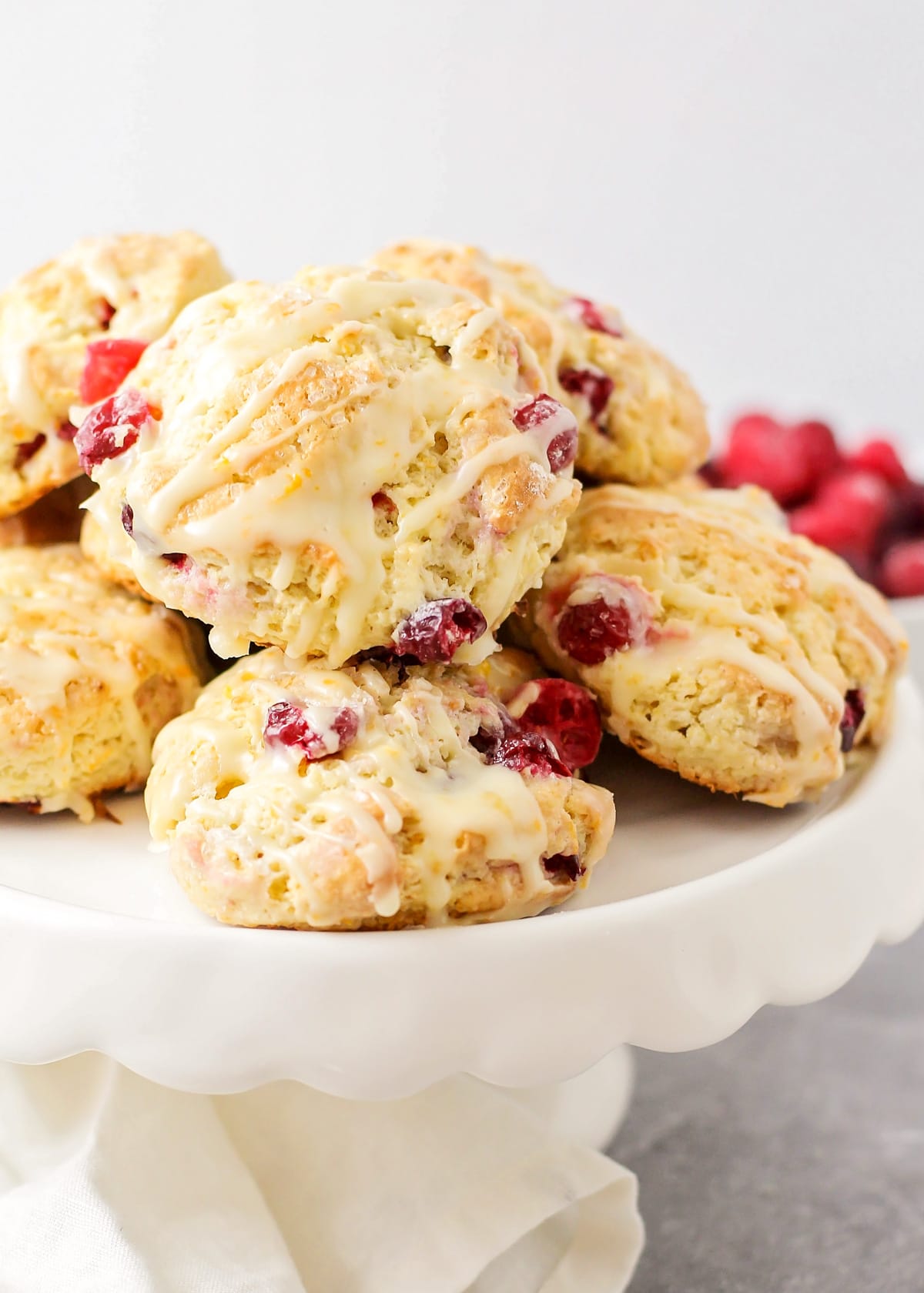 Close up of glazed cranberry orange scones on a white plate.