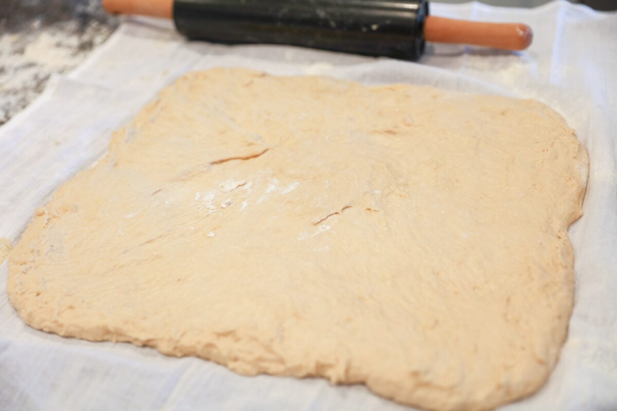 Easy cinnamon roll dough rolled out on tea towel.