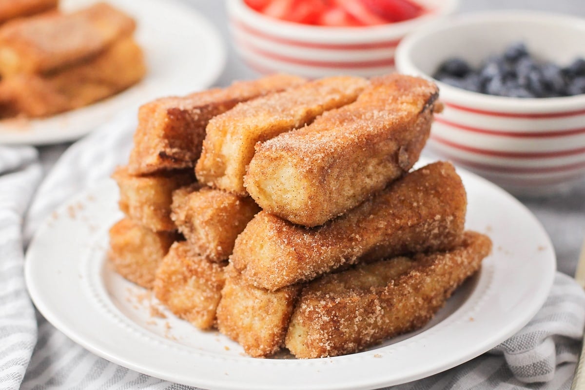 French toast sticks recipe - all stacked on a white plate.