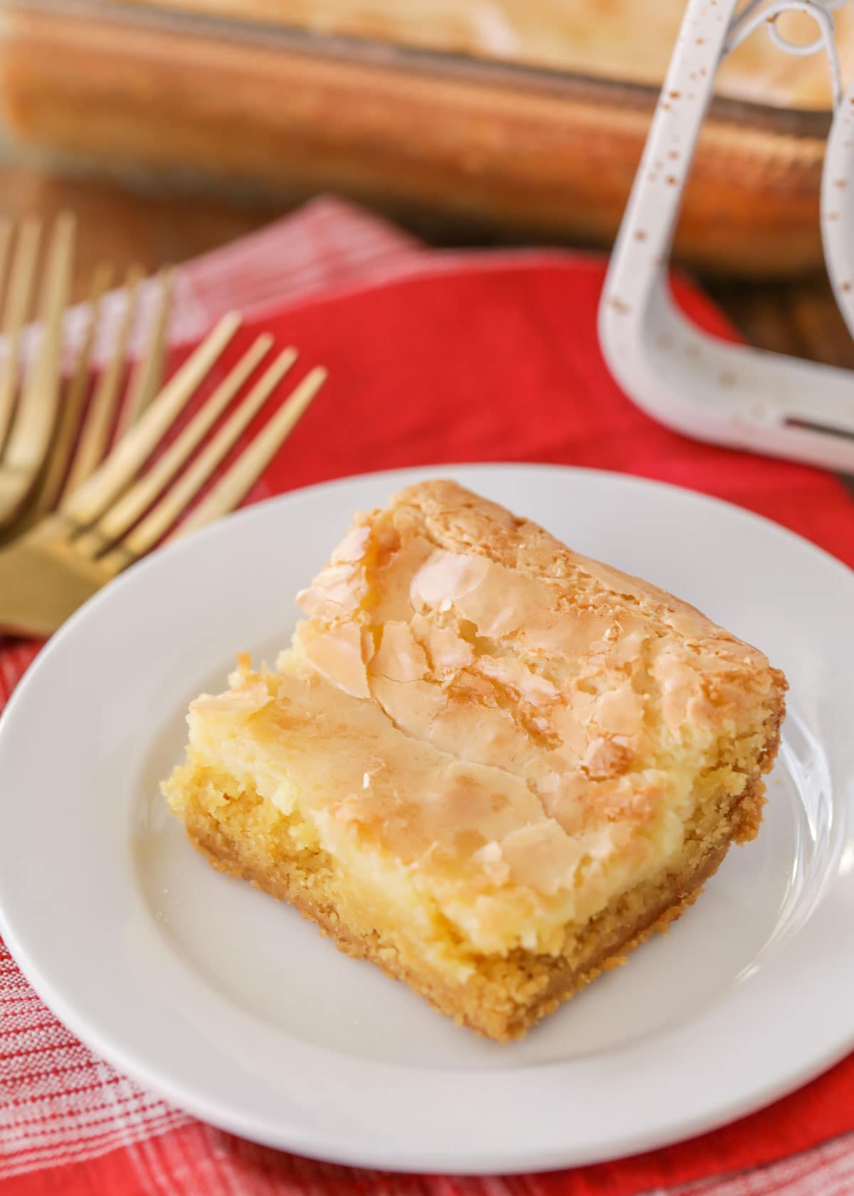 A slice of ooey gooey butter cake on a white plate