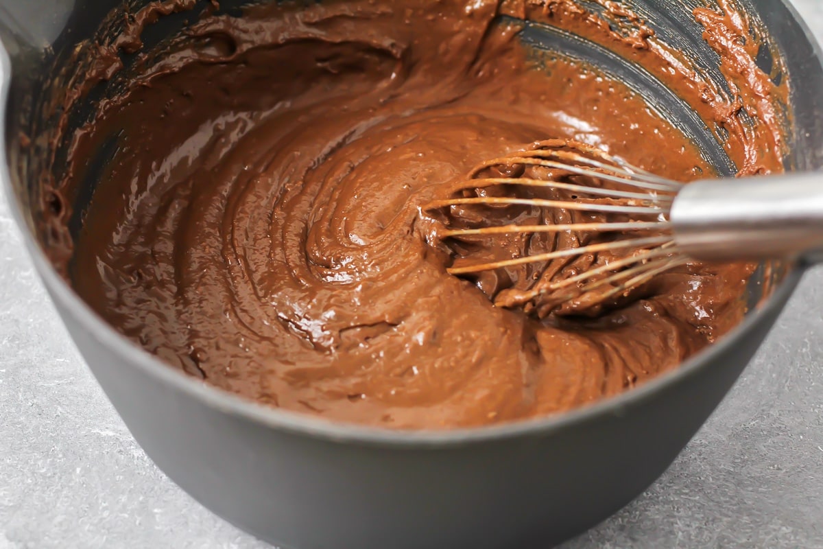Mixing chocolate cake batter in a gray bowl.