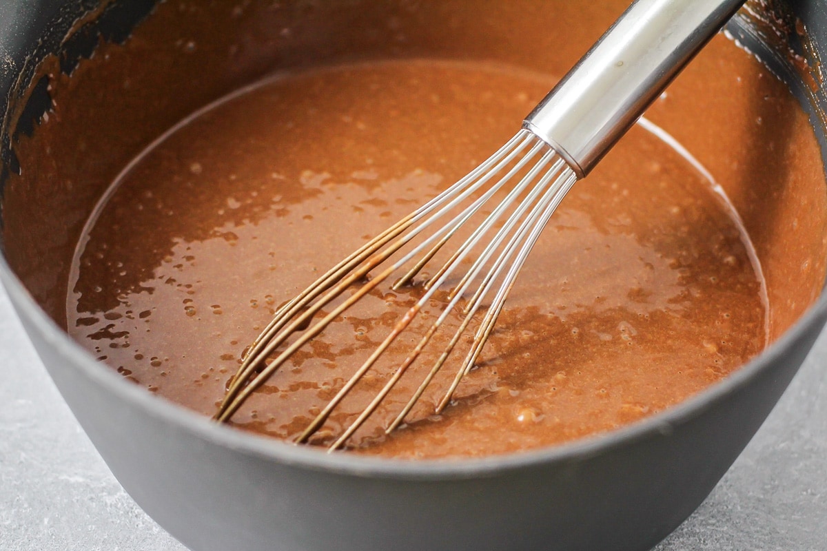 Whisking chocolate cake batter in a gray bowl.