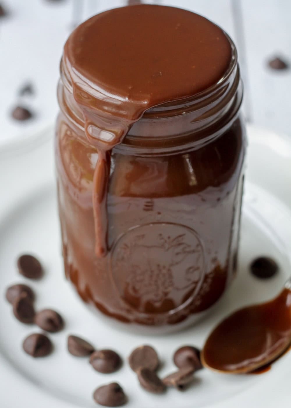 Homemade hot fudge sauce recipe in glass mason jar spilling over.