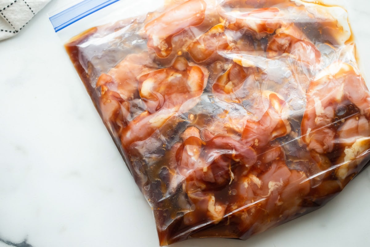 Chicken marinating in a Ziploc bag.