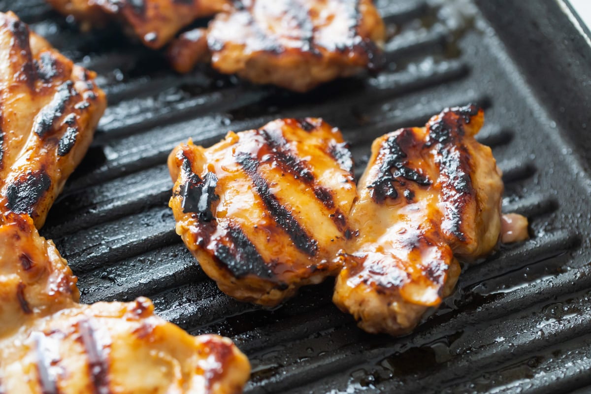 Marinated chicken grilling on a grill pan.