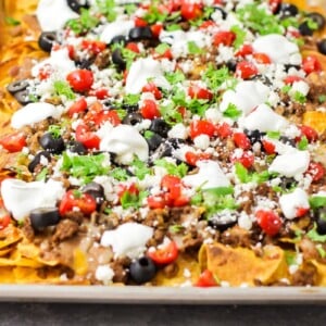 A sheet pan of our nachos recipe loaded with toppings.