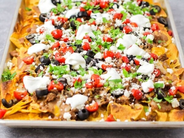 A sheet pan of our nachos recipe loaded with toppings.