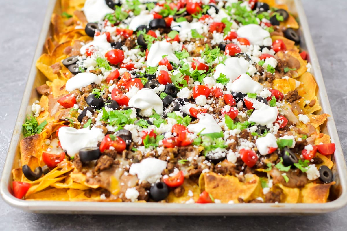 A close up of a loaded sheet pan filled with nachos recipe.