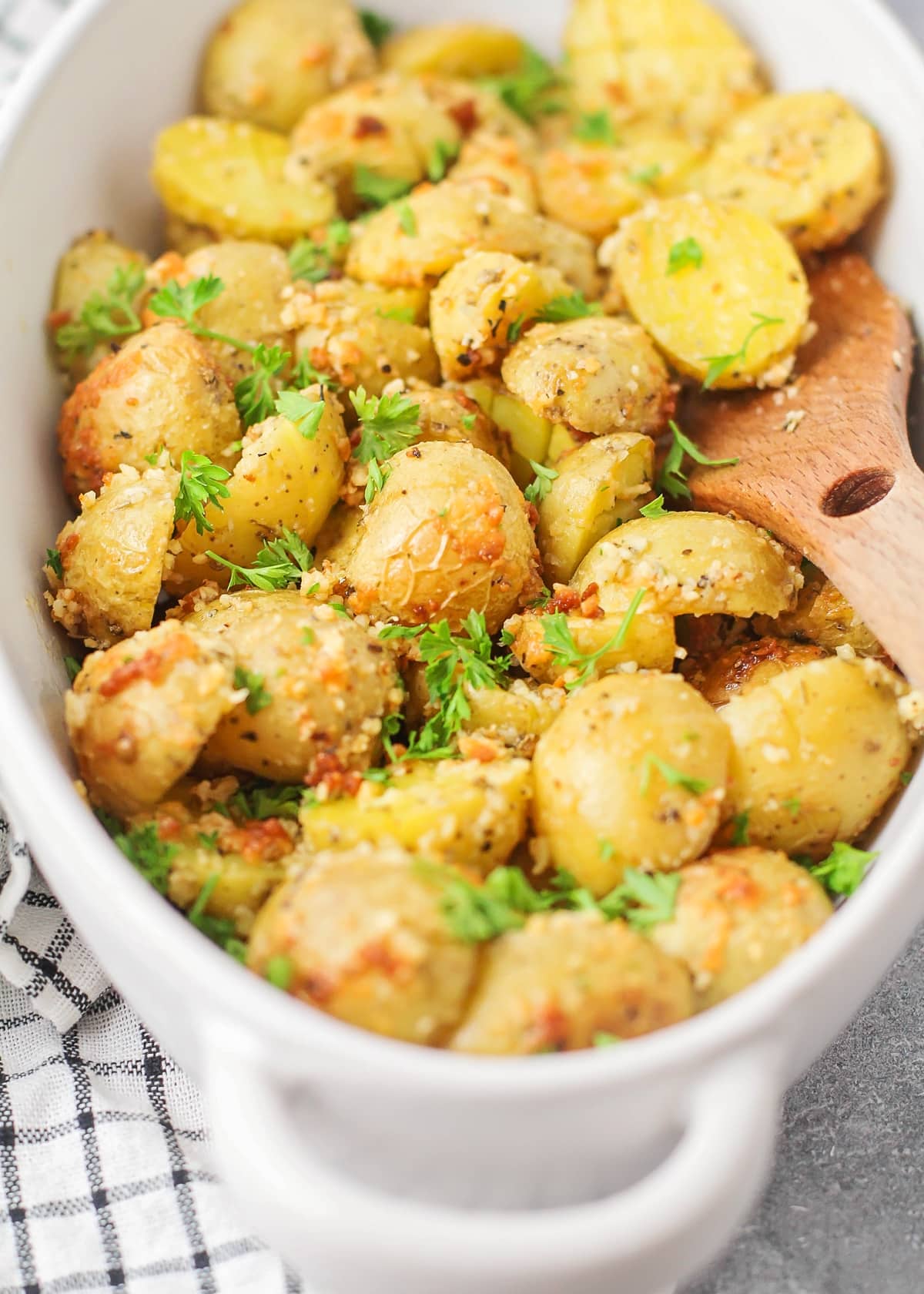 Close up of parmesan crusted potatoes cooked and topped with fresh herbs.