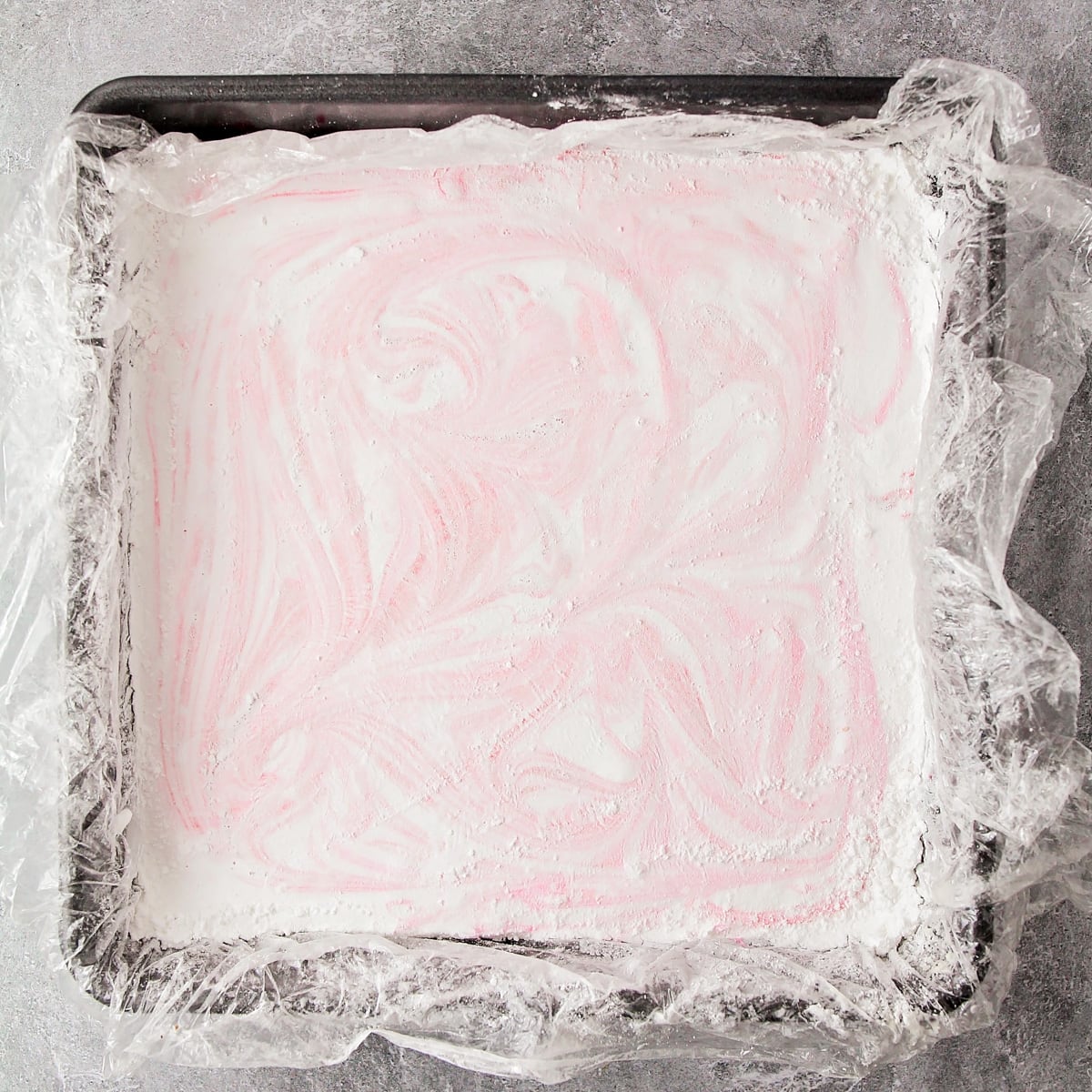 Red swirl marshmallow mixture in a metal pan.