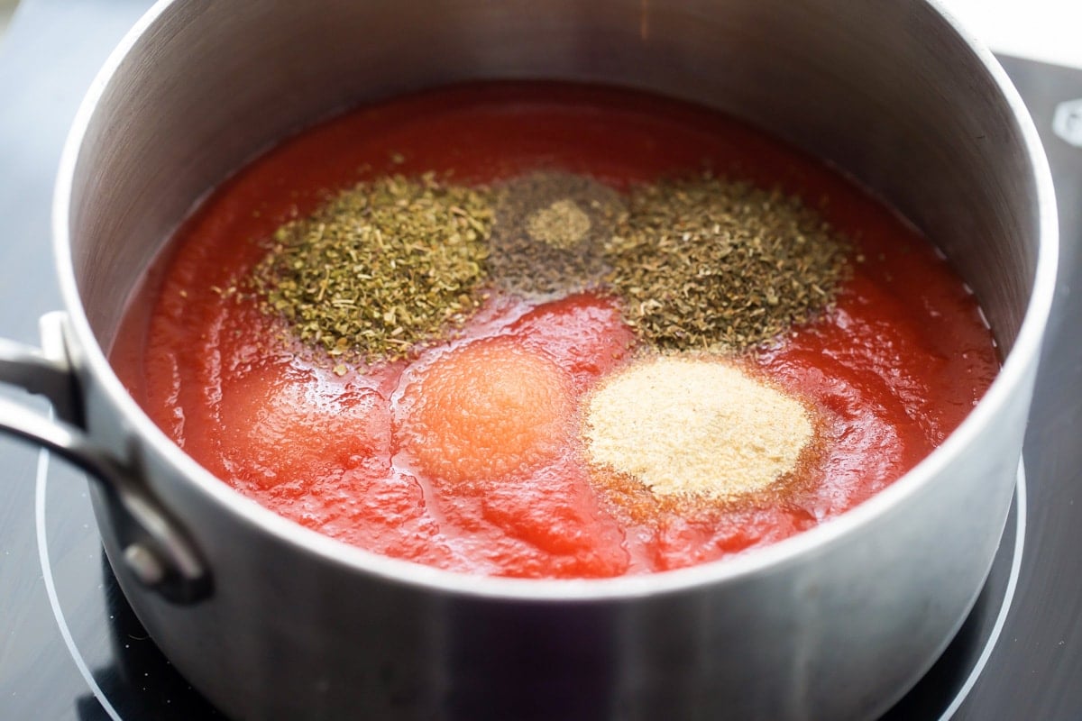 Pizza sauce seasonings poured into tomato sauce.