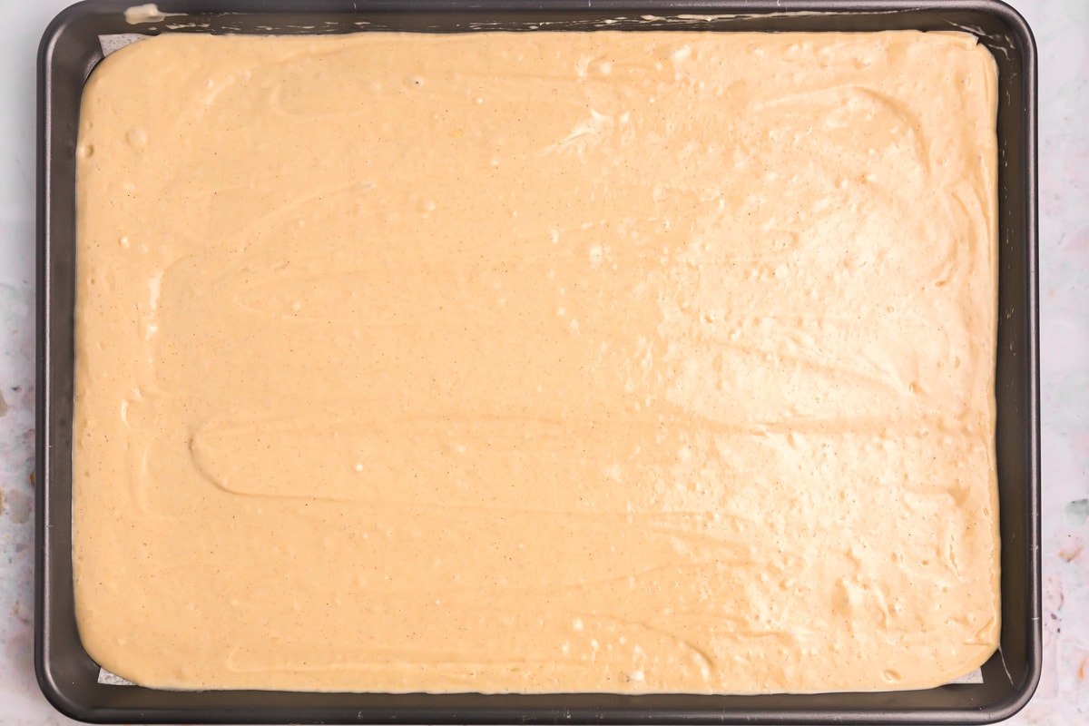 Pancake batter spread out on a lined sheet pan.