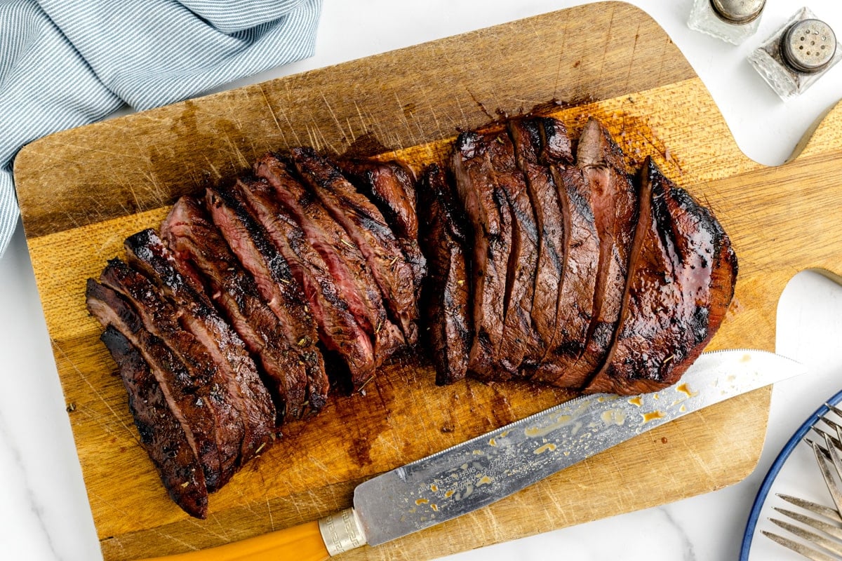 Two steaks sliced on a cutting board.