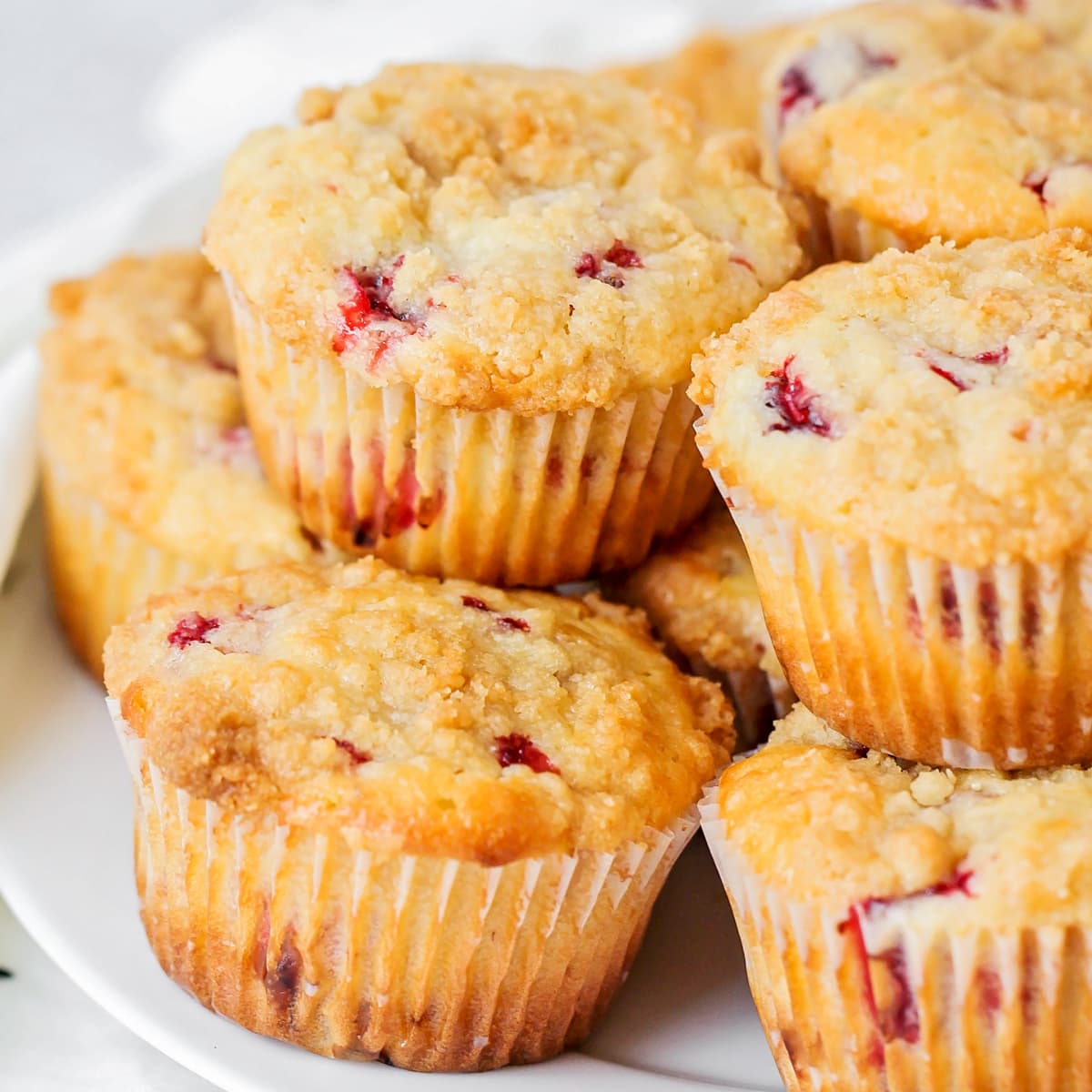 Close up of strawberry muffins piled on a white plate.