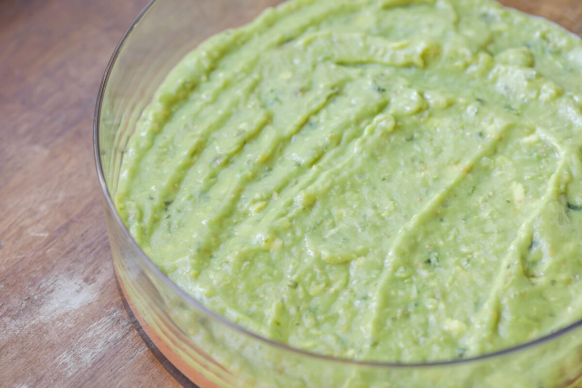 Layer of guacamole over beans for bean dip.