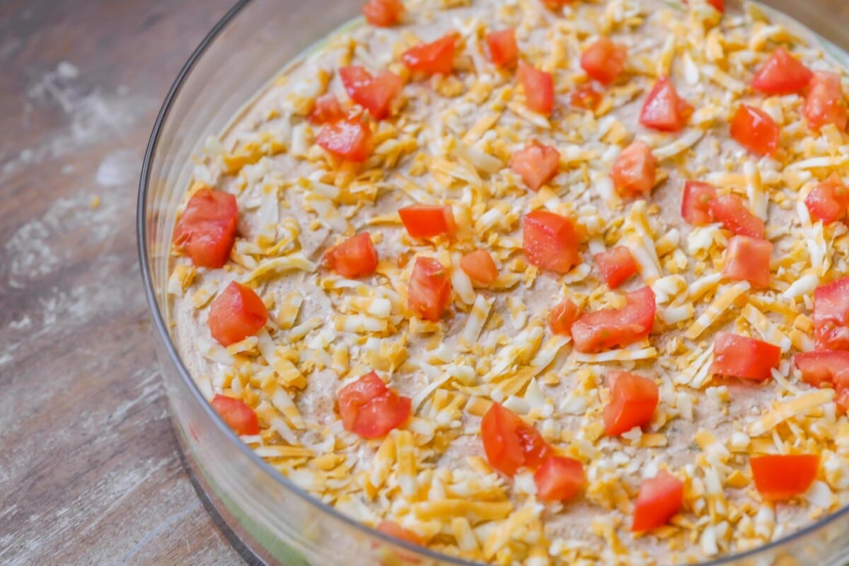 Cheese and tomatoes on layer of 7 layer bean dip.