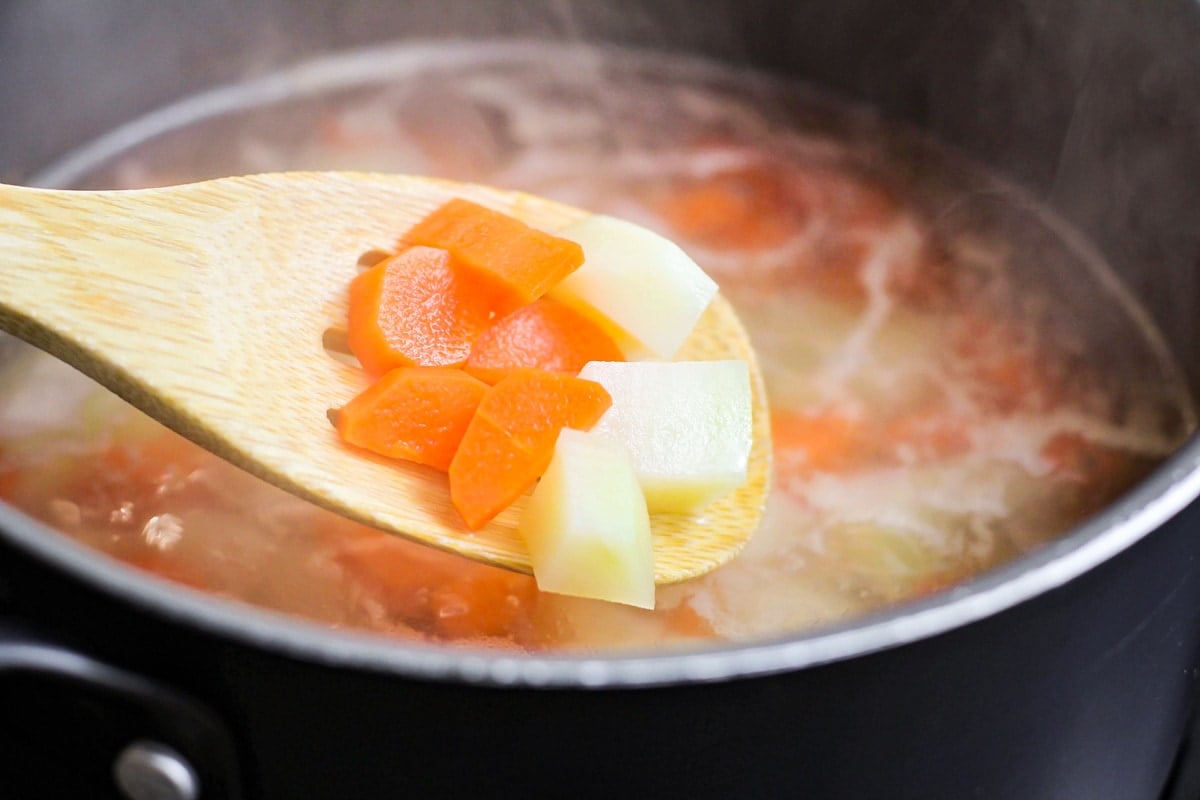 Cooking potatoes and carrots into a pot of water.
