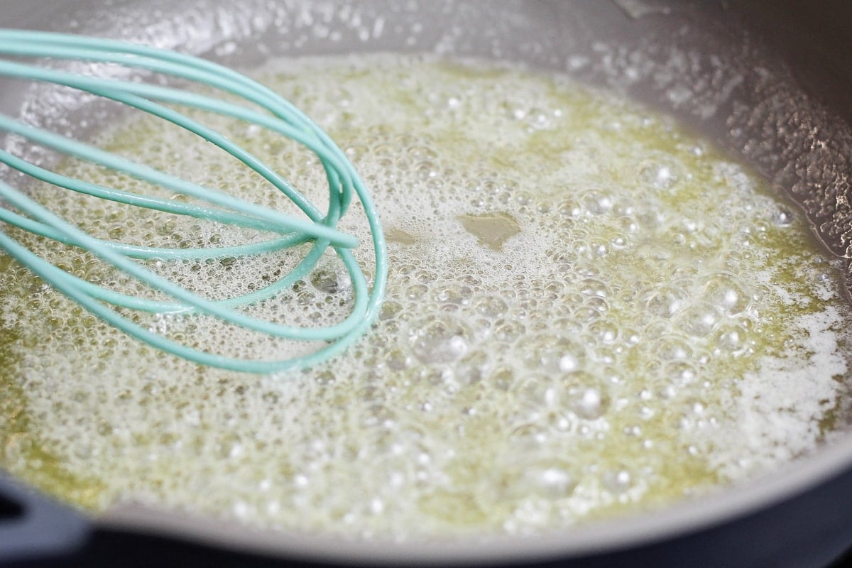 Whisking butter in a skillet on the stove.