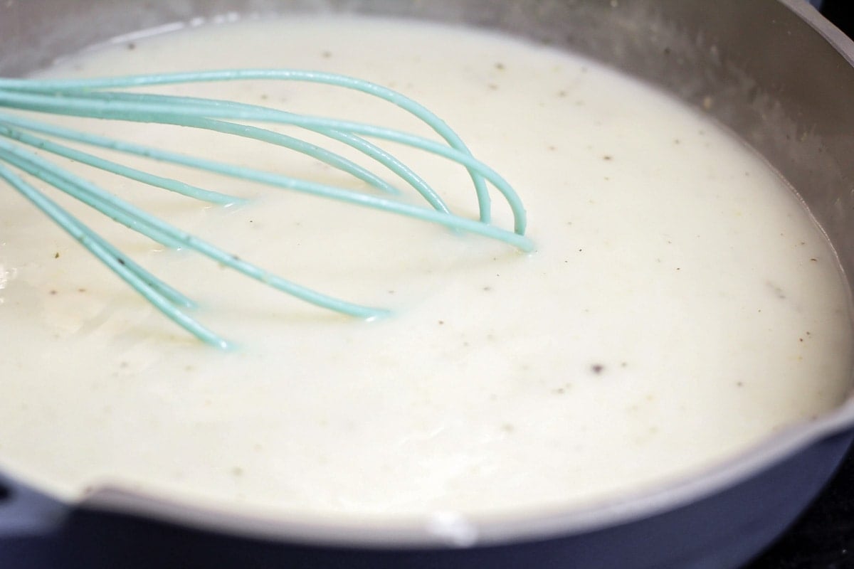 Whisking a roux in a skillet on the stove.
