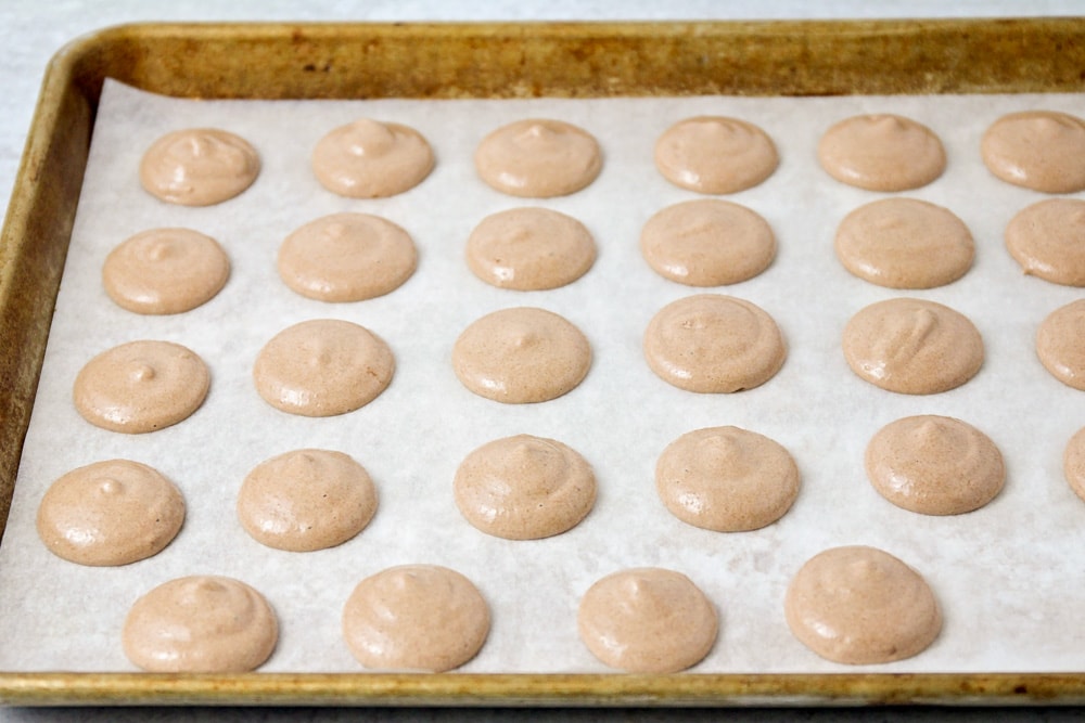 Macarons piped onto parchment paper.