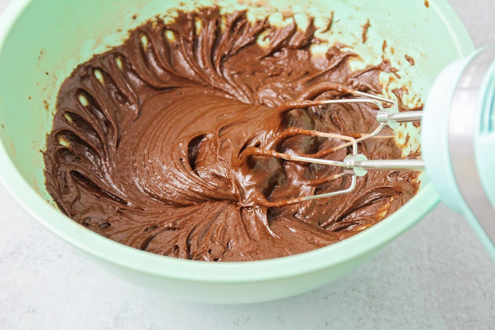 Mixing chocolate cupcake batter in a mint bowl.