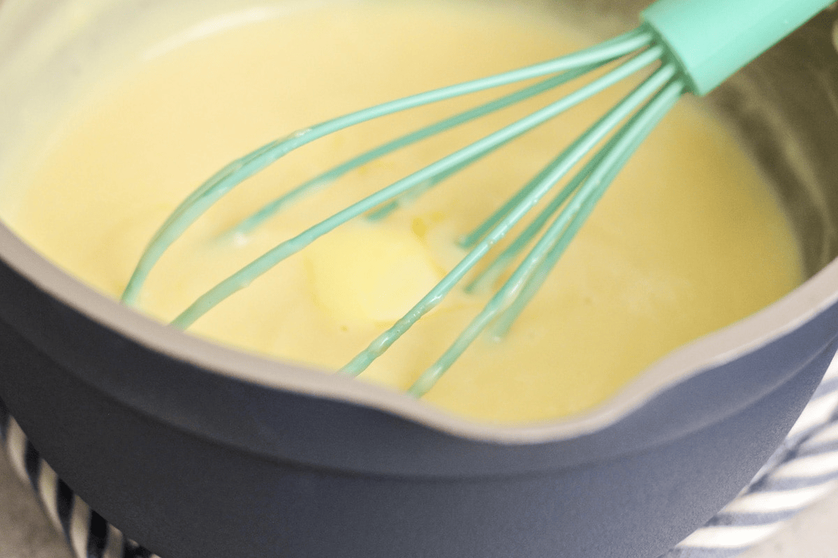 Whisking butter into a thickened mixture in a bowl.