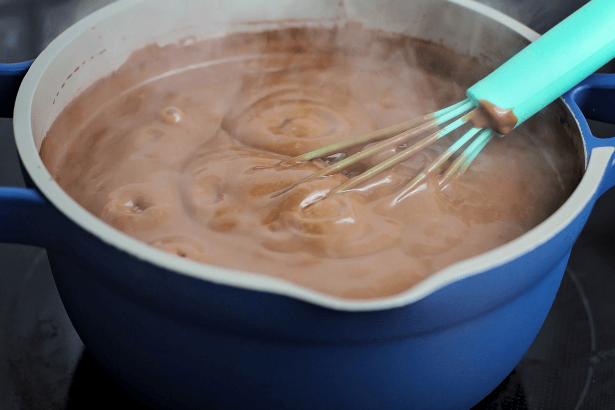 A pot on the stove filled with a boiling chocolate mixture.