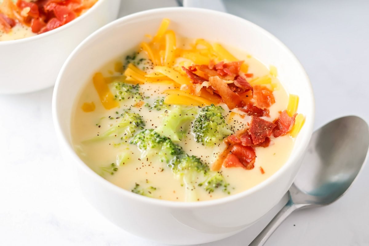 Broccoli cheese soup recipe in bowl with spoon next to it.