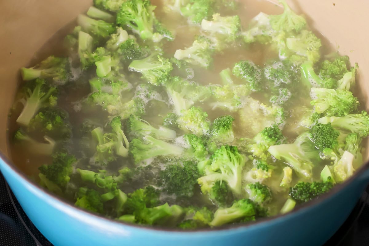 Broccoli cooking in a pot of water for broccoli cheese soup.