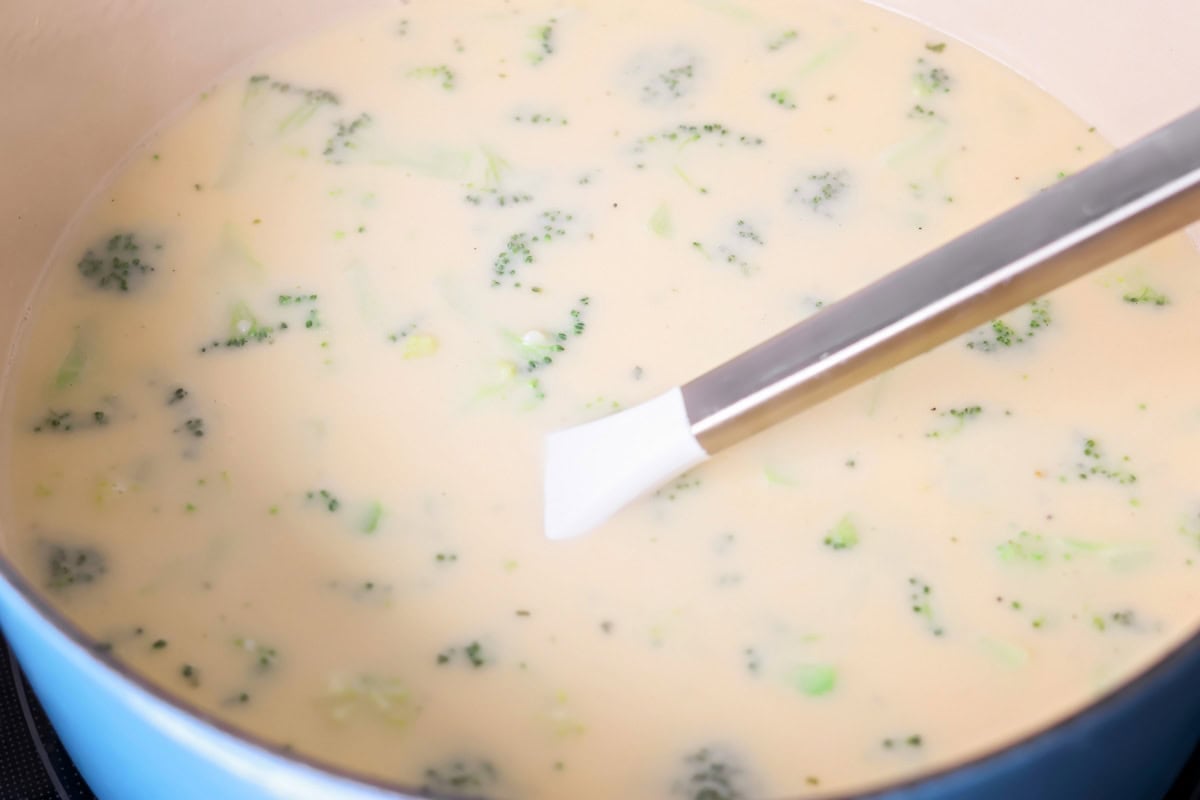 Stirring broccoli cheese soup in a pot.