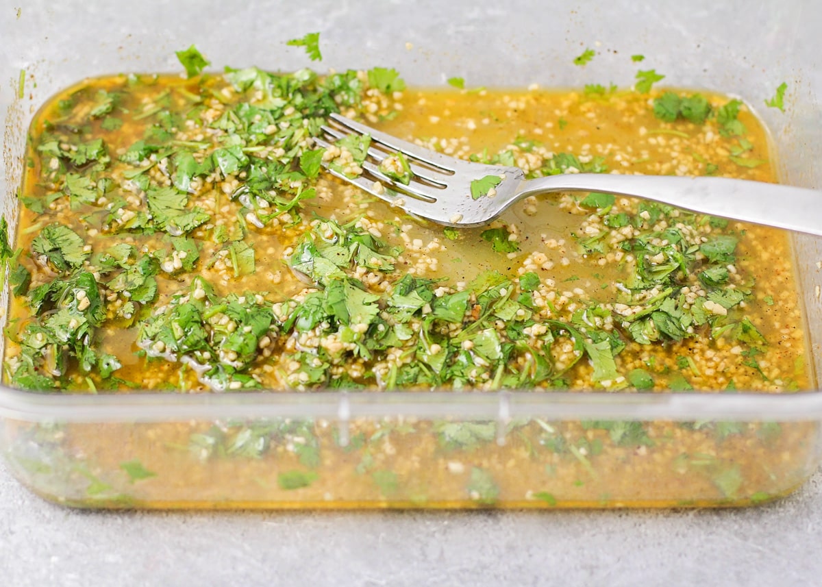 Marinade mixed with cilantro in a glass baking dish.