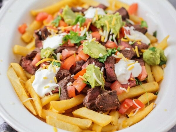 A platter of carne asada fries packed with toppings.