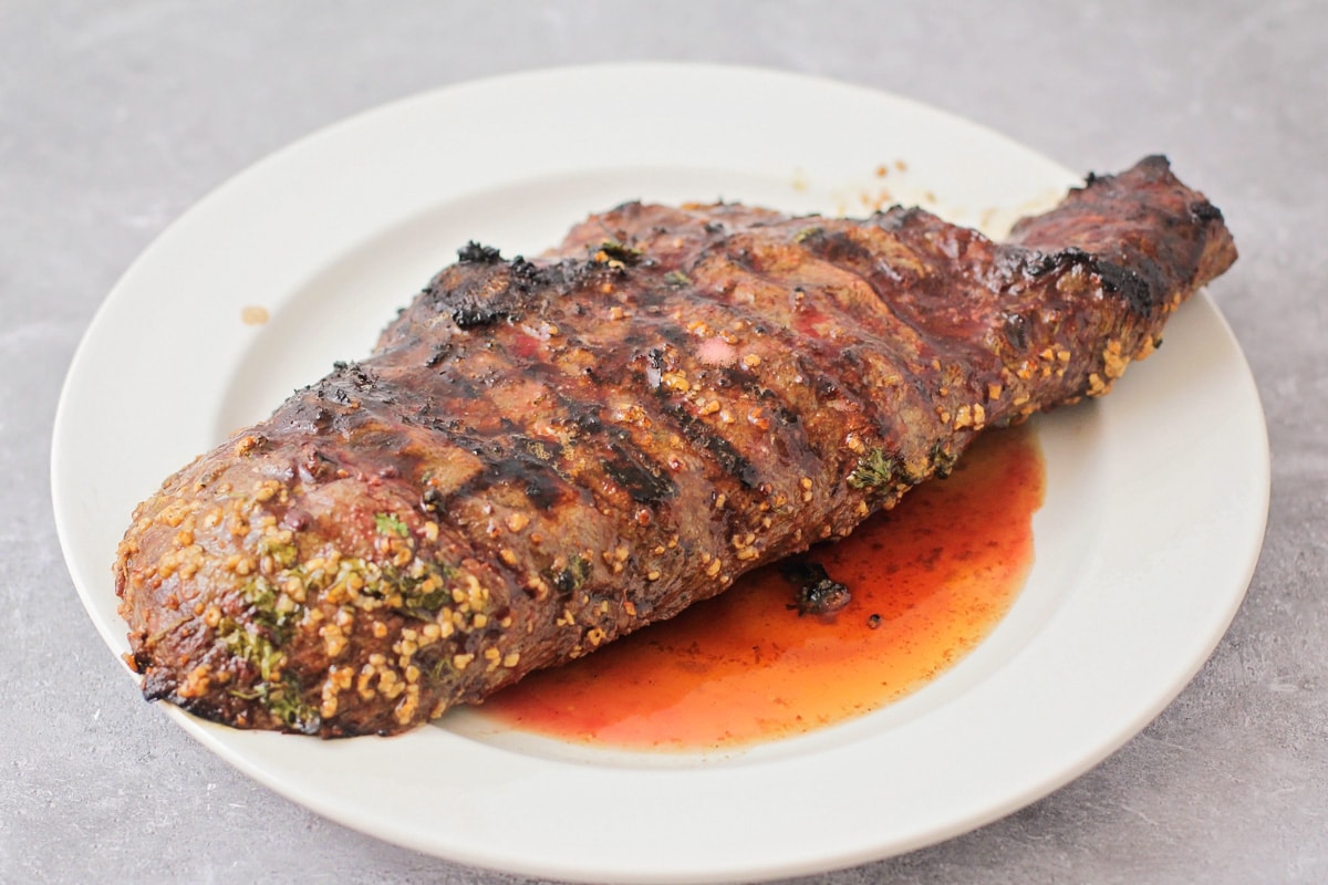 A grilled steak resting on a white plate.