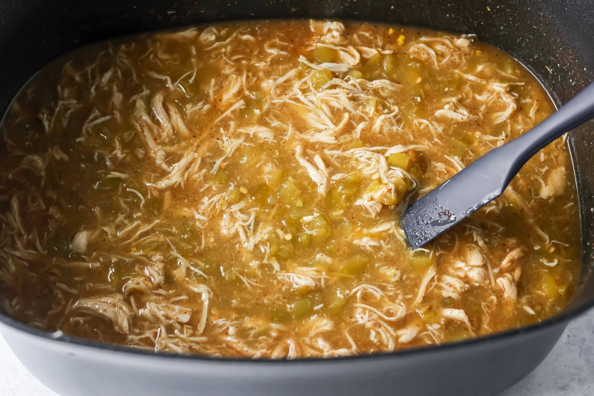 Combining ingredients for chicken enchilada soup in a crock pot.