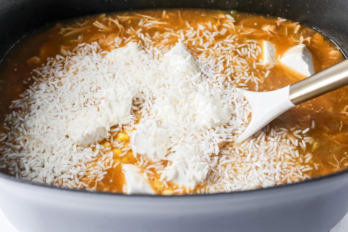 Adding rice to chicken enchilada soup.