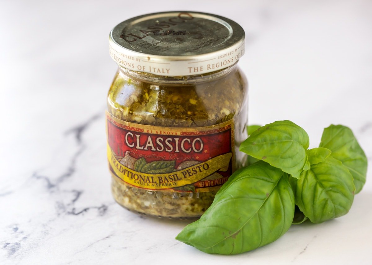 A small jar of pesto sauce on a kitchen counter.