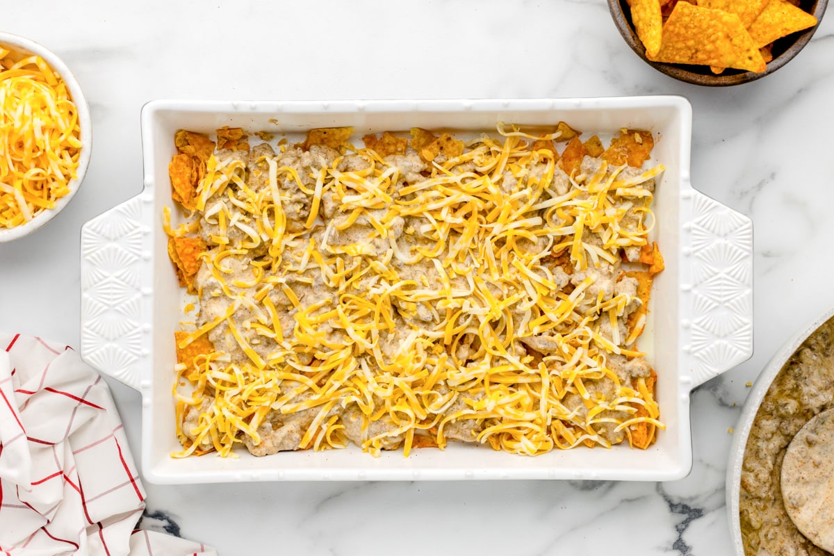 Shredded cheese over layers in baking dish.
