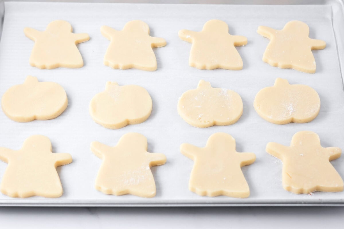 Halloween sugar cookies cut out on parchment paper lined cookie sheet.