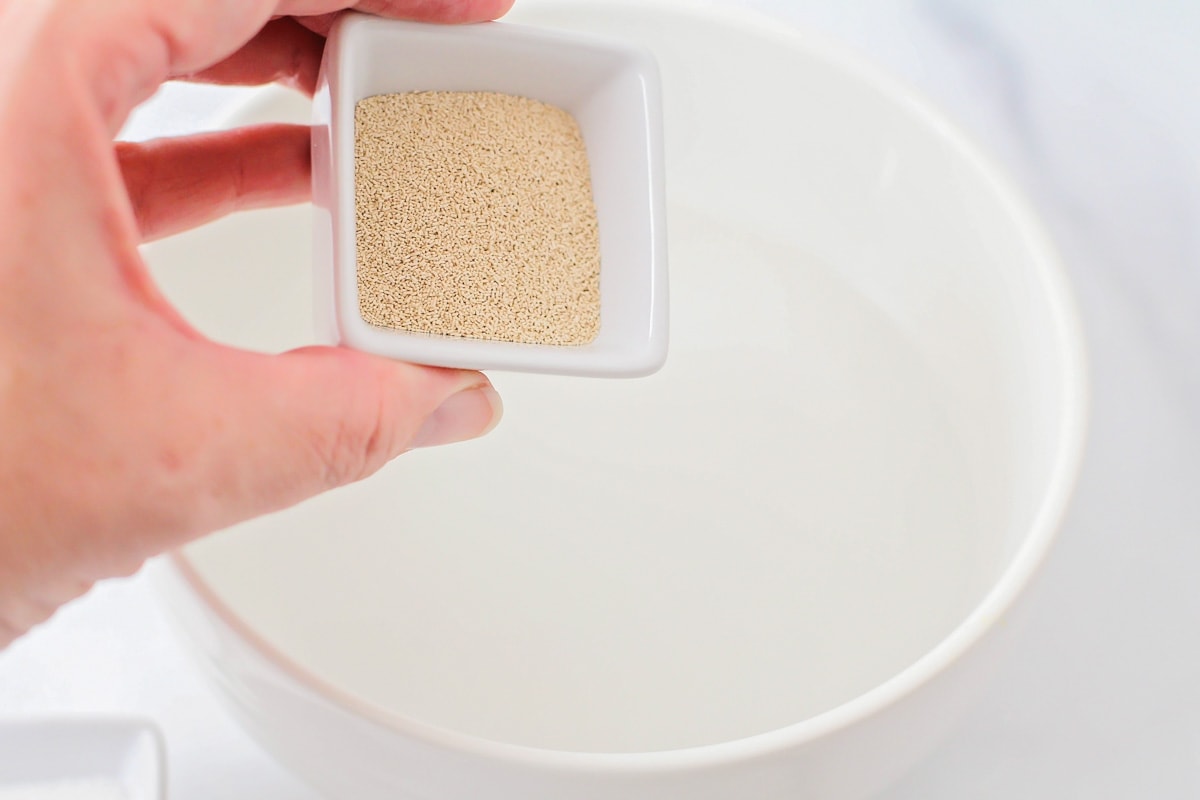 Adding yeast to a bowl of warm water.
