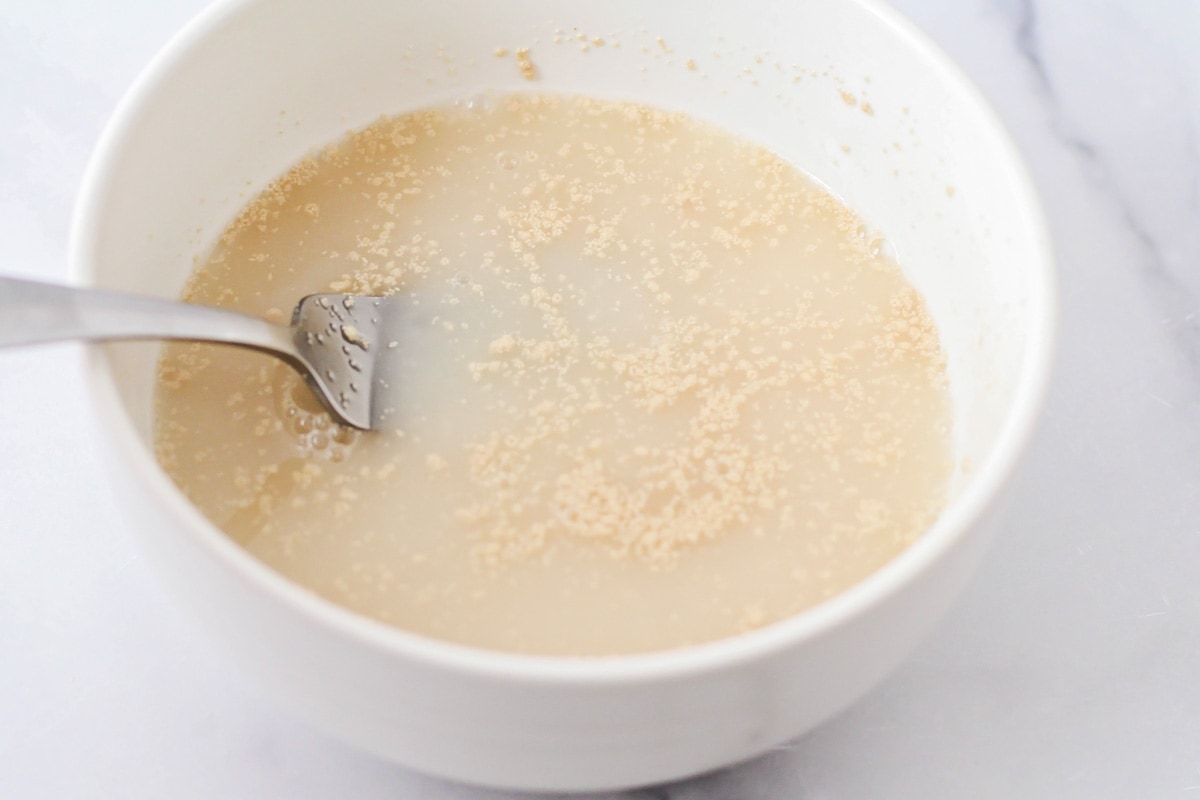 Mixing yeast into a bowl of warm water.