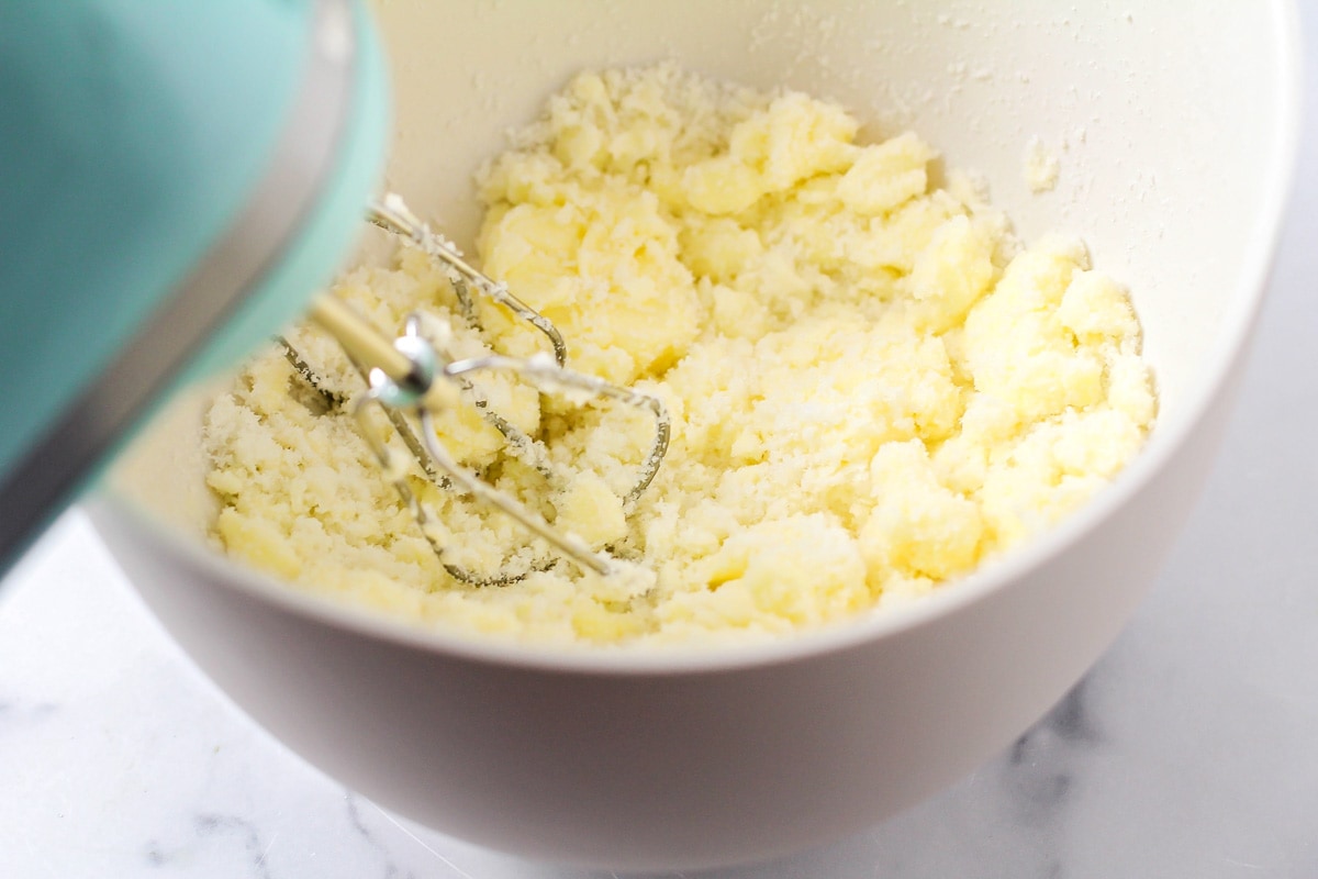 Sugar added to a bowl of butter and being mixed.